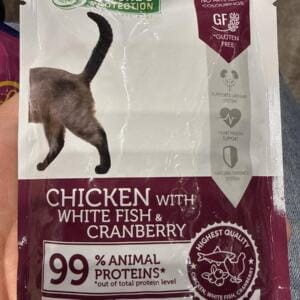 Пакет корму для котів з зображенням хвоста кота, що містить курку, білу рибу та журавлину.