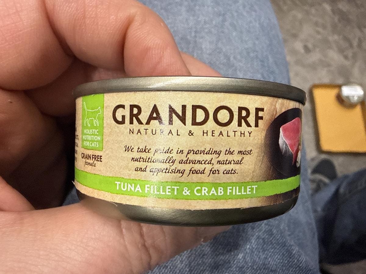 Консерви для котів Grandorf Консервна банка корму для котів з тунцем і крабом в руці.